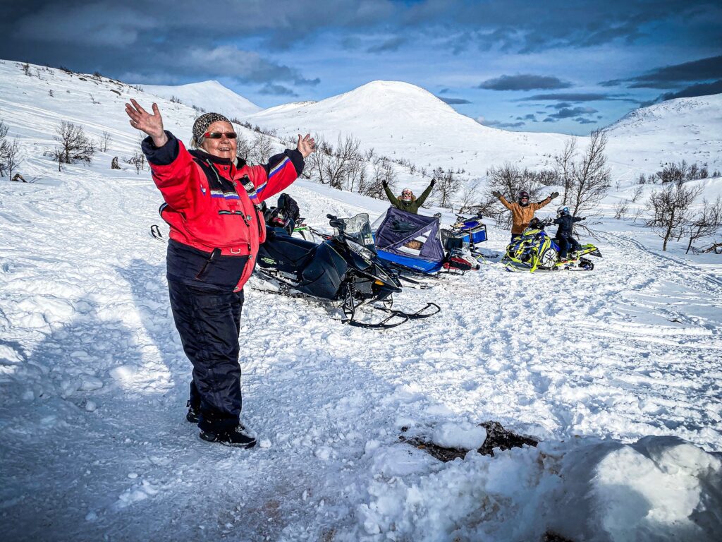 Group of People Celebrating and Raising Hands in Snowmobile Gear